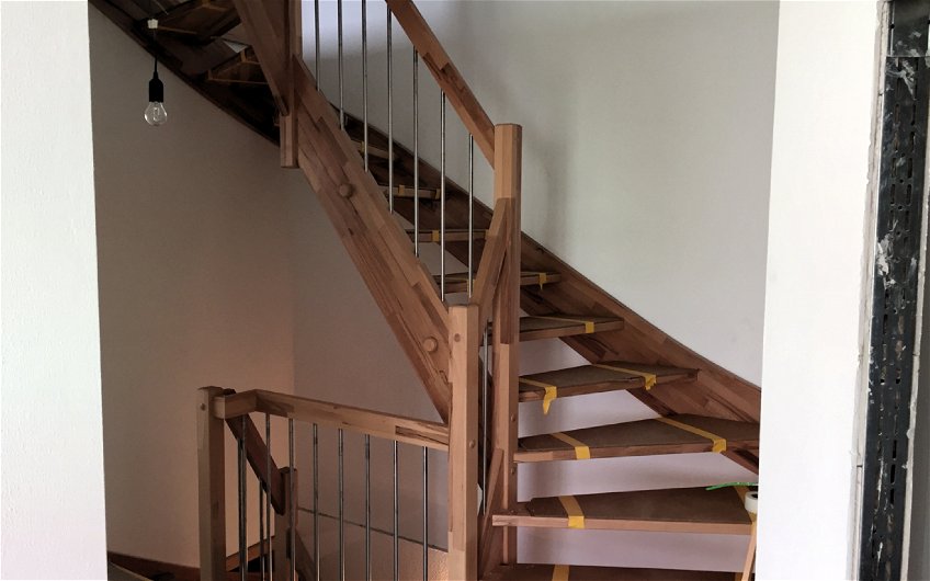 Flur mit Treppe mit Geländer aus Holz.