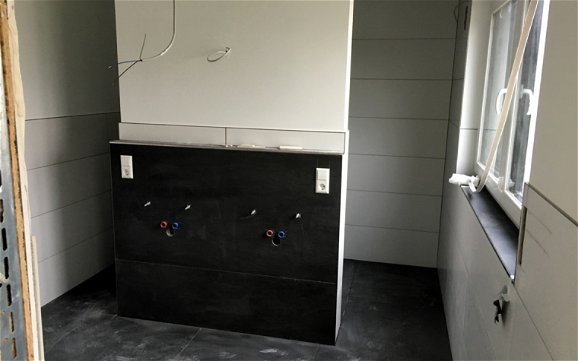 Blick in das Badezimmer auf Installationswand für zwei Waschbecken.