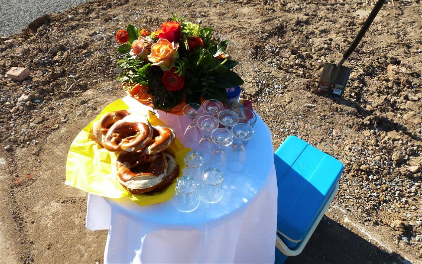 Kleiner gedeckter runder Tisch mit Brezeln, Gläsern und Blumenstrauß.
