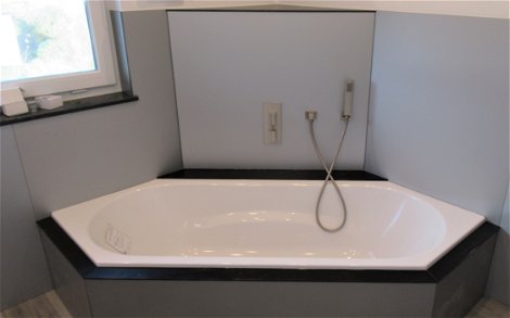 Die komfortable Sechseck-Badewanne wurde mit Platten verkleidet.