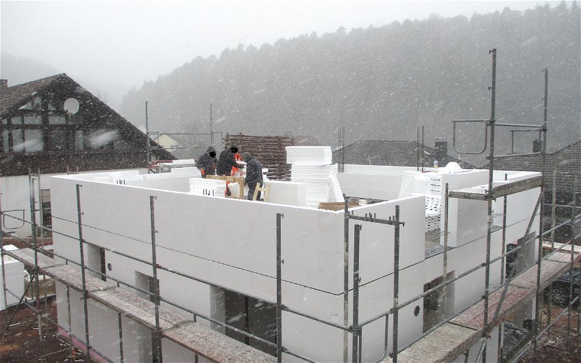 Die Bauarbeiter geben alles und erstellen den Rohbau trotz Schneefall.