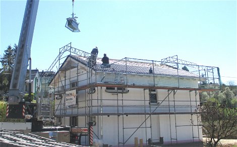 Ein Kran erleichtert das Verlegen der Dachpfannen auf dem Dach.