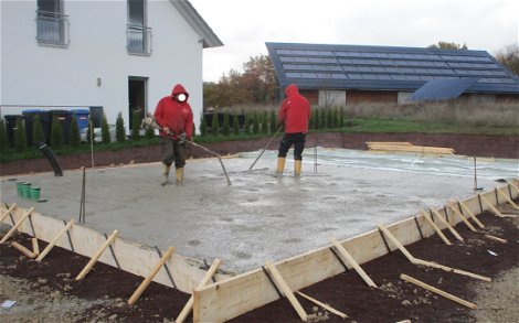 Fleißige Bauarbeiter betonieren die Bodenplatte.