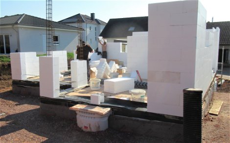 DuoTherm-Elemente wurden auf die Baustelle geliefert und fleißige Bauarbeiter beginnen mit dem Aufbau des Kern-Hauses.