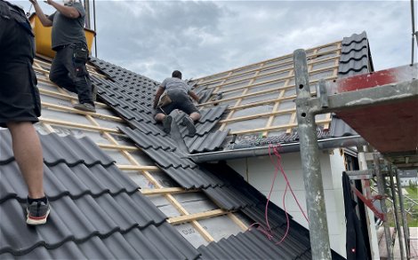 Die Dachdecker verlegen die Dachsteine und sichern diese zum Schutz vor Wind und Sturm.