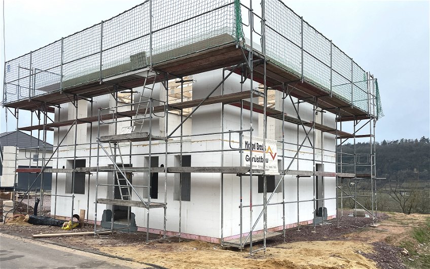 Für Zimmermann- und Dachdeckerarbeiten wird das Außengerüst mit zusätzlichen Sicherheitsmaßnahmen erweitert.